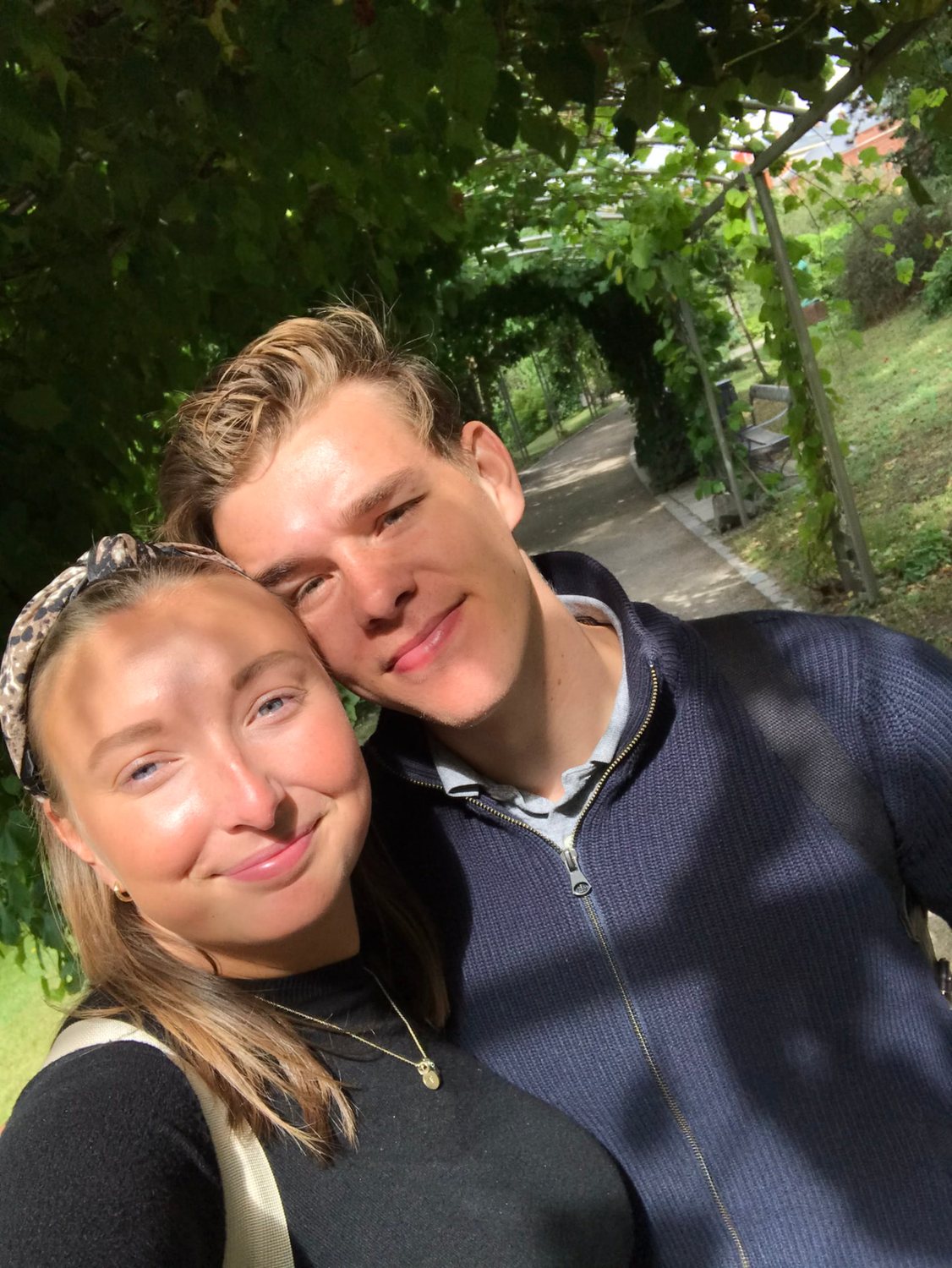 Filip och Josefin kind mot kind på en solig trädgårdsstig