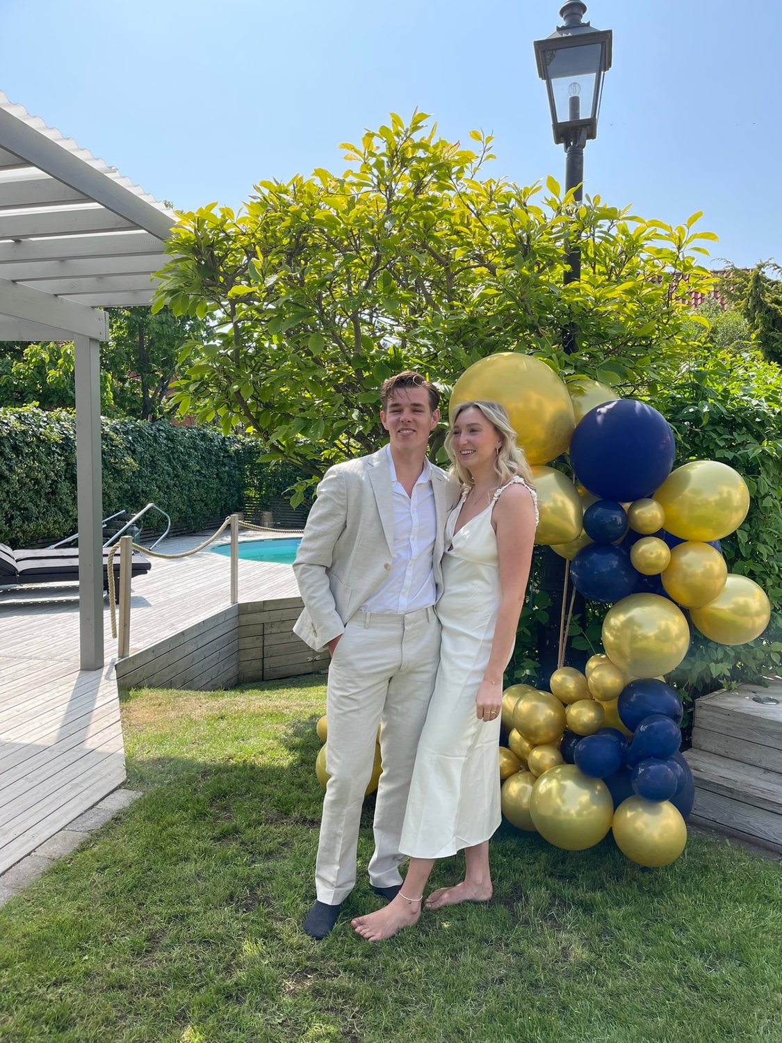 Filip och Josefin i festkläder bland ballonger vid en pool