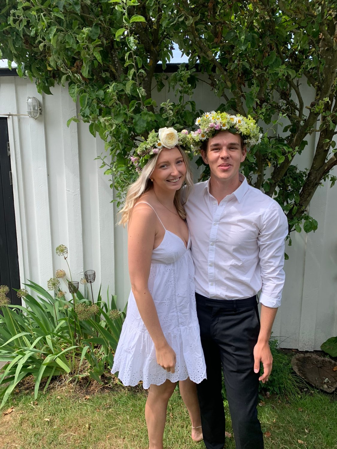 Filip och Josefin med blomsterkransar i en lummig trädgård